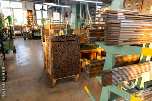 Blick in eine helle industrielle Holzwerkstatt mit präzise gestapelten Holzelementen und Maschinen zur Fertigung