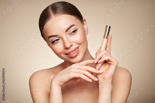 Portrait beautiful young woman with clean fresh skin. Model with foundation makeup bottle. Cosmetology, beauty and spa