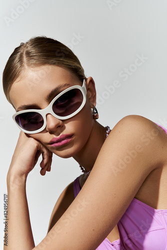 Blonde woman looking fashionable in pink swimsuit and sunglasses.