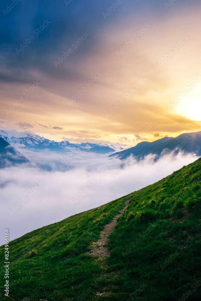View of a green mountain road with a sea of clouds below the Pyrenees mountains at sunset. Vall d'Aran, catalonia, Spain