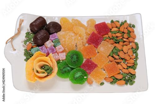 Marmalade, candied fruit, mango, kiwi, nuts, seeds, chocolate candies and Turkish delight in a plate. Variety of sweet desserts in plate.