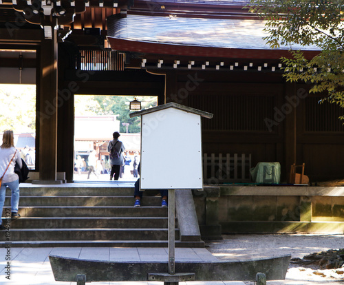 Old, empty wooden grey, dark brown sign stands next to entrance to temple in Japan. People walking around and temple entrance in background. Clipping path.