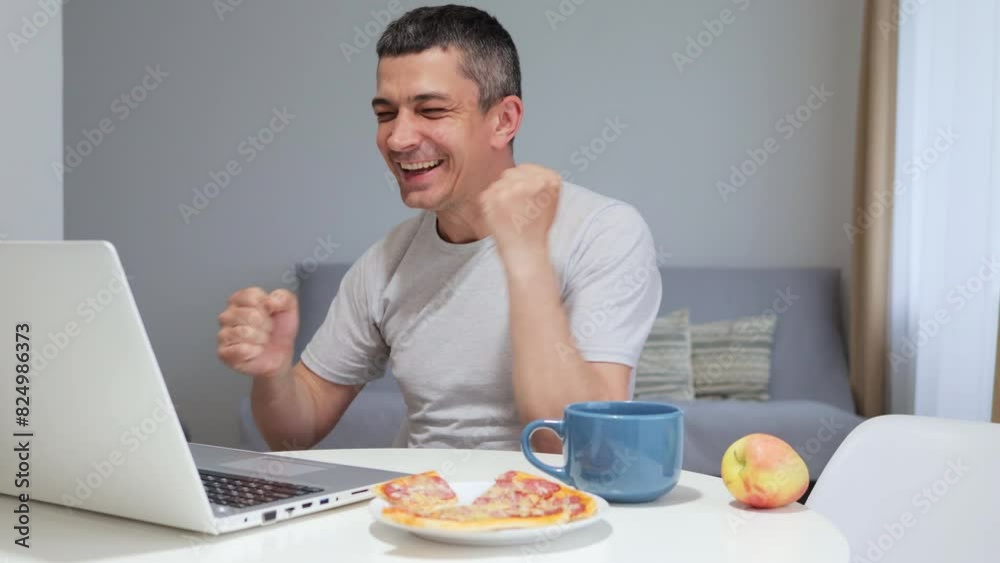 Extremely happy overjoyed man using laptop computer working at home office celebrating his success clenched fists exclaiming with excited facial expression Extremely happy overjoyed man using laptop computer working at home office celebrating his success clenched fists exclaiming with excited facial expression