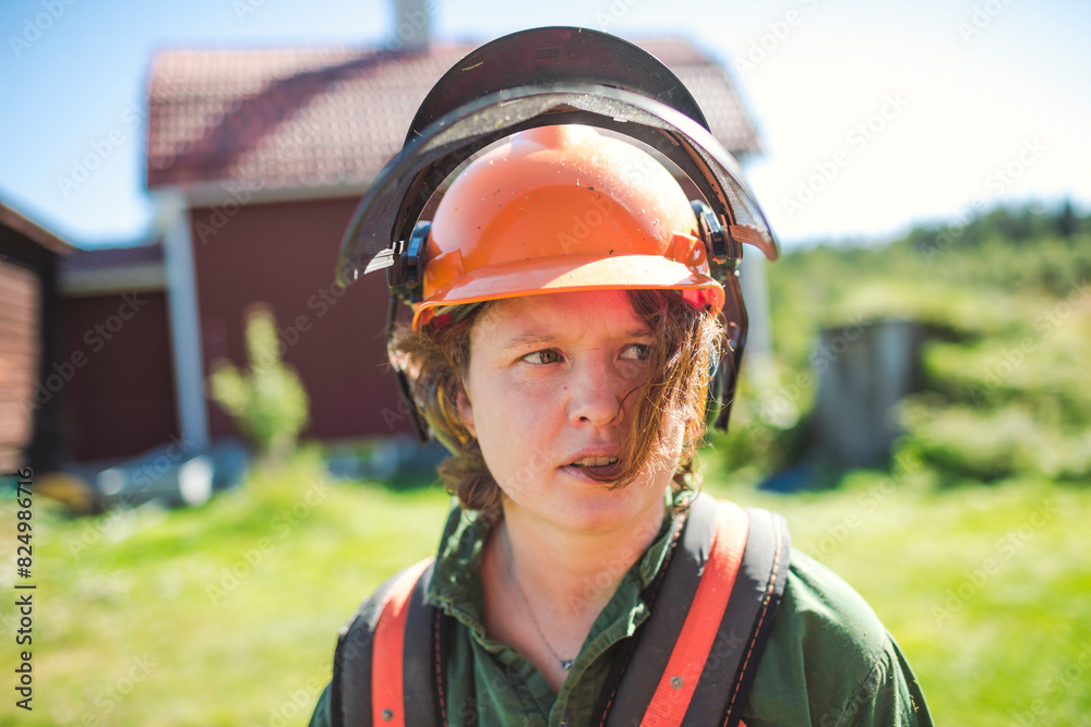 Woman in protective workwear looking away at yard Woman in protective workwear looking away at yard