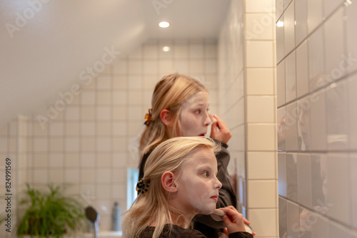 Blond girls applying make-up in bathroom photo