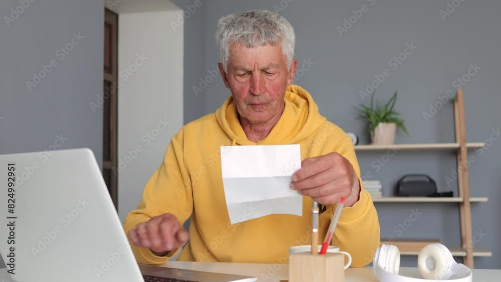 Senior Caucasian man searching on internet using laptop paying bills online holding document typing on keyboard doing paperwork savings, paying domestic bills mortgage loan pension at home Senior Caucasian man searching on internet using laptop paying bills online holding document typing on keyboard doing paperwork savings, paying domestic bills mortgage loan pension at home