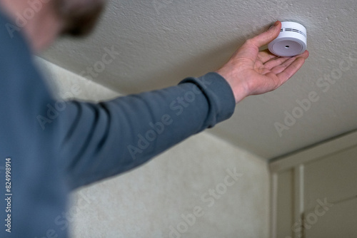 Man installing smoke detector on ceiling at home photo