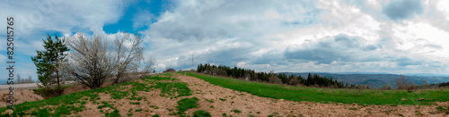 Panorama of the spring forest near the mountain town. Picturesque landscape of a sunny day.