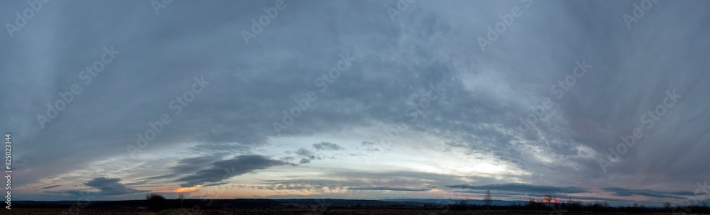 Panorama of dawn fire in the sky above the natural pasture. Golden red clouds just before sunrise. Picturesque landscape at sunrise. Beauty in nature