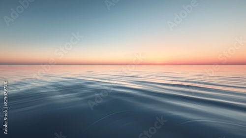 A serene landscape featuring a calm lake reflecting the soft colors of the sunset, with gentle ripples on the water's surface and a smooth, cloudless sky above. photo