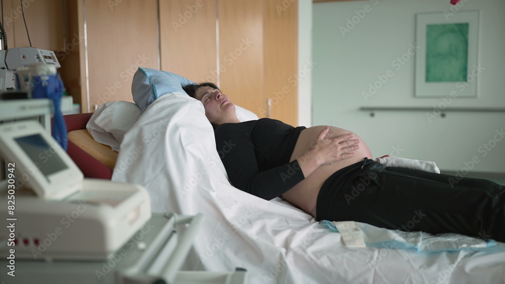 Obraz premium Pregnant woman laid at hospital bed resting during prelabor contractions, late stage pregnancy at clinic setting