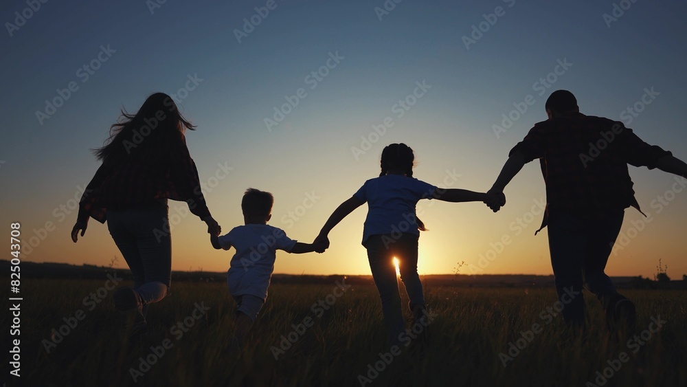 family runs across the field. happy childhood concept for little child. big happy family running across the field on the grass holding hands, sunset lifestyle on the background, silhouettes