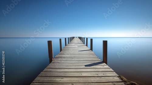 A long wooden pier stretching out into a tranquil ocean  with no people  capturing the stillness of the water under a cloudless blue sky.