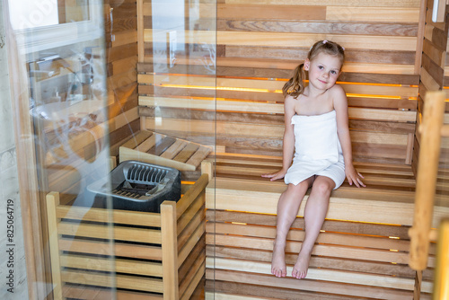 фотографія Little girl sits in the sauna and warms herself