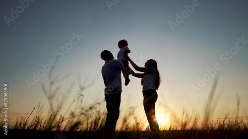 family standing on the field. happy childhood concept for little child. big happy family stands on field, parents raised the child lifestyle in their arms, sunset on the background, silhouettes