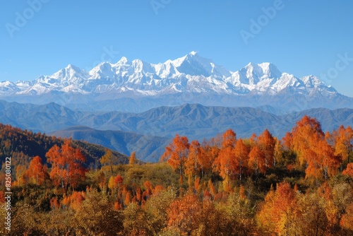The mountains are covered in snow and the trees are orange. The sky is blue and clear. The scene is peaceful and serene
