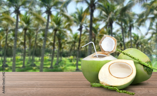 Coconut juice (coconut water) and fresh young green coconut with coco nut plantation blur background.