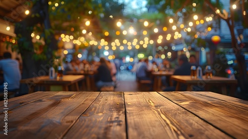 Empty wooden table top with blurred background of outdoor restaurant in the evening for product display montage. 