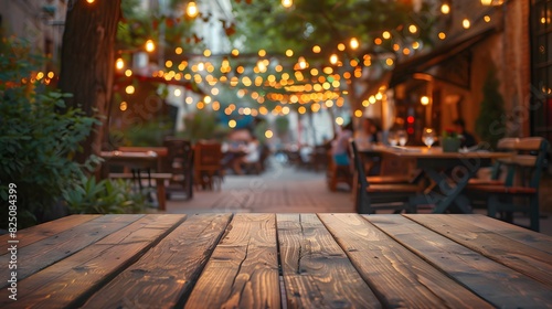 Empty wooden table top with blurred background of outdoor restaurant in the evening for product display montage. 