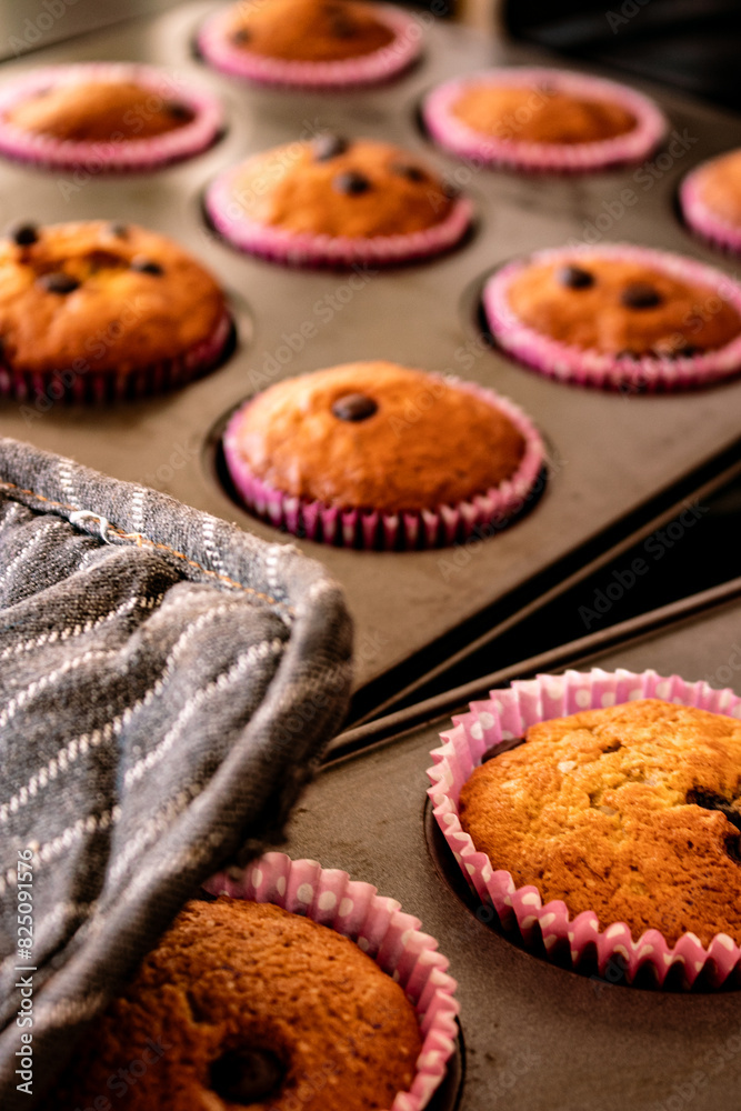 Fresh banana/chocolate chip muffins in muffin trays with pink cupcake papers Fresh banana/chocolate chip muffins in muffin trays with pink cupcake papers