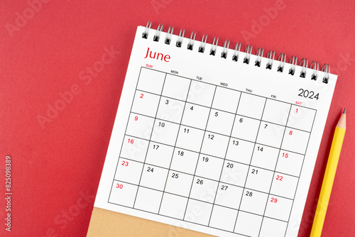 June 2024 desk calendar and pencil on red background. © gamjai