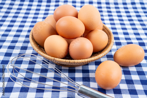 The Fresh raw eggs in the basket on blue tablecloth