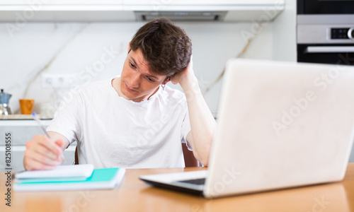 Young guy studying at home with laptop