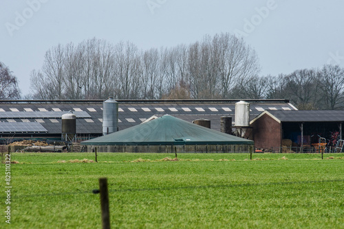 manure digester near a farm with cow stable, barn and silos