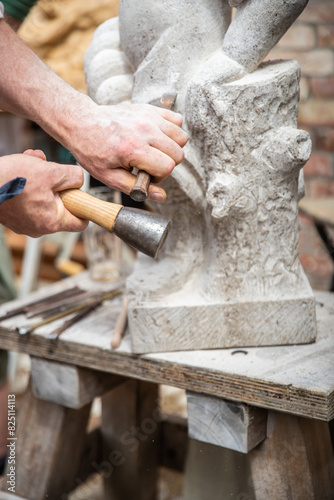 Schilderij op canvas Ein Steinmetz arbeitet mit einem Hammer und Meißel an einer Statue