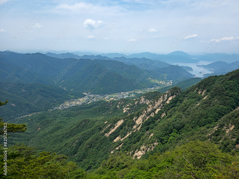 Obraz premium A mountain range with a town in the valley below. The sky is clear and the sun is shining