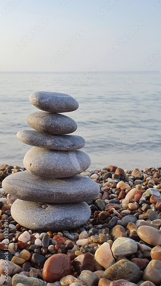 Spa stones balance on the sand of the beach.