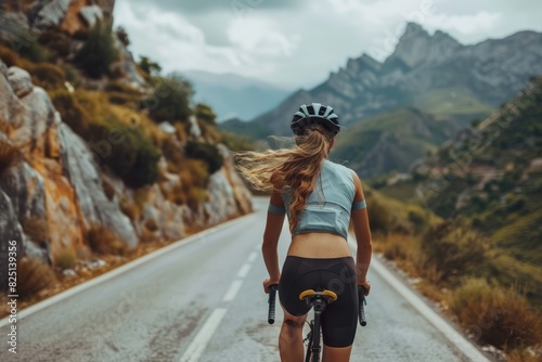 Una hermosa ciclista rubia joven entrenando en una carretera de montaña. 