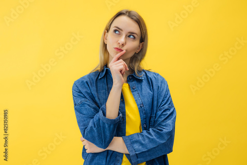 Pensive suspicious attractive woman looking for answers on her questions isolated on yellow background