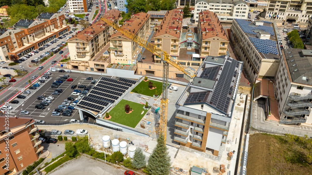 Fototapeta premium Aerial view of industrial tower crane operating in a newly built neighborhood. These large machines allow the concrete plates weight balance.
