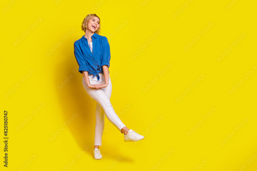 Full size photo of pretty young girl dance look empty space wear shirt isolated on yellow color background Full size photo of pretty young girl dance look empty space wear shirt isolated on yellow color background