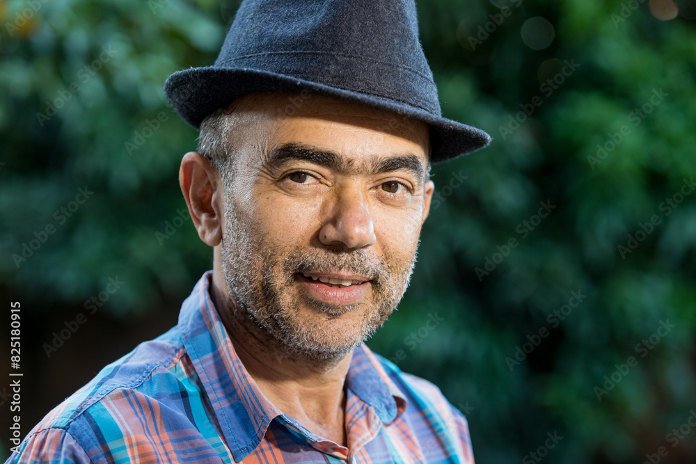 50-year-old man, wearing a black hat, gray beard, wearing prescription glasses. Mature, confident and smiling. face portrait