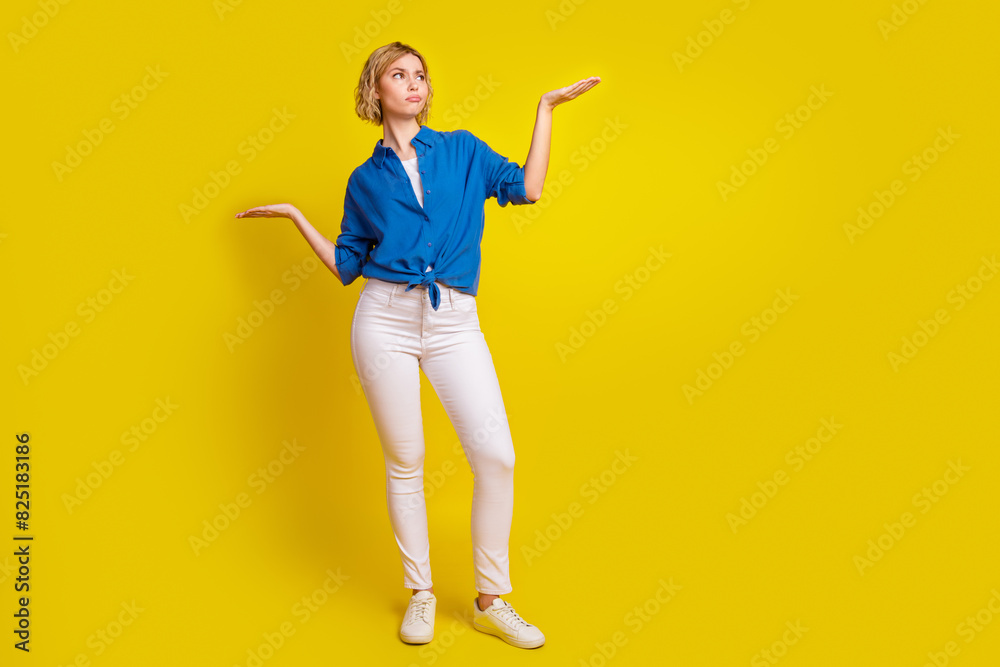 Full size portrait of pretty young lady hands hold empty space wear shirt isolated on yellow color background Full size portrait of pretty young lady hands hold empty space wear shirt isolated on yellow color background