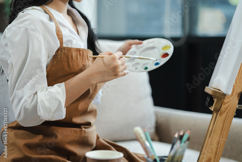 Young female artist painting on canvas in the home studio, fine arts and creativity concept.