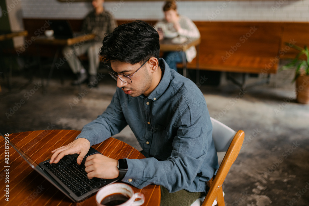 A man uses a laptop in a cafe A man uses a laptop in a cafe