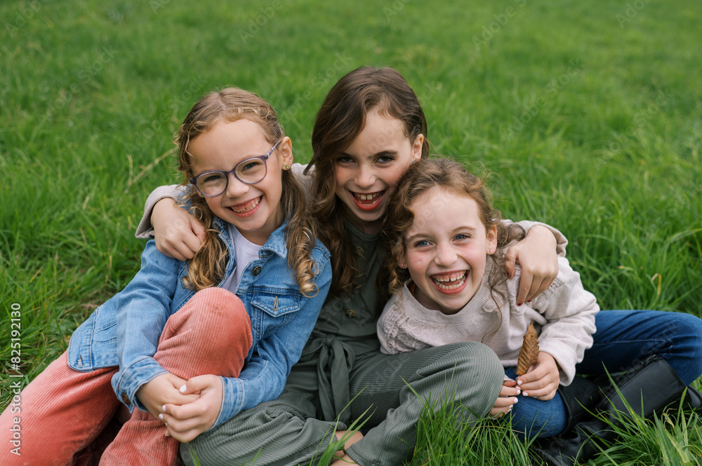 Portrait of kids sitting in grass together and laughing Portrait of kids sitting in grass together and laughing