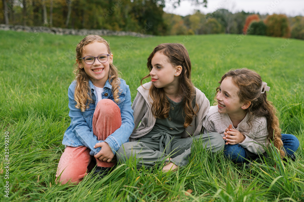 Portrait of kids sitting in grass together and laughing Portrait of kids sitting in grass together and laughing