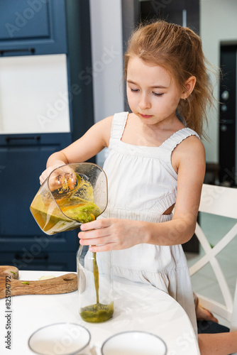 A little girl pours juice into a bottle. 