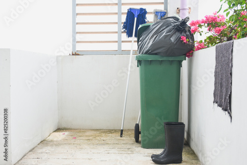 green trash can Black boots and garbage bags