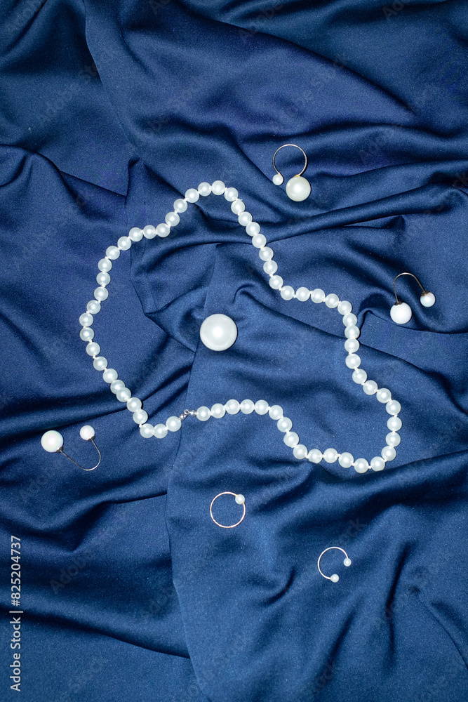Classic white pearl jewellery on blue silk with hard direct flashlight Classic white pearl jewellery on blue silk with hard direct flashlight