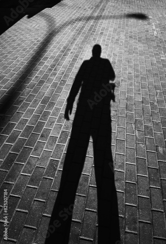 Man's shadow on street pavement tiles backdrop