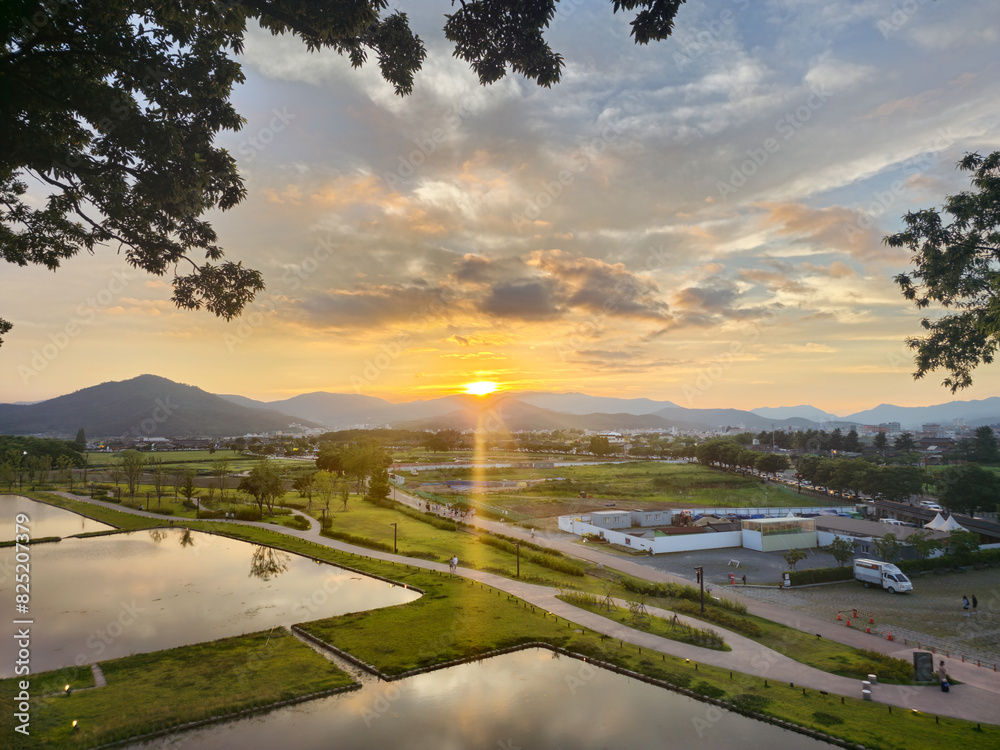 A beautiful sunset over a city with a large body of water in the background. The sky is filled with clouds, creating a serene and peaceful atmosphere A beautiful sunset over a city with a large body of water in the background. The sky is filled with clouds, creating a serene and peaceful atmosphere