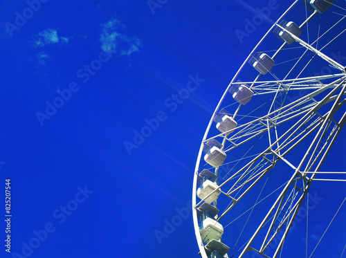 Right aligned white Ferris wheel on blue sky backdrop