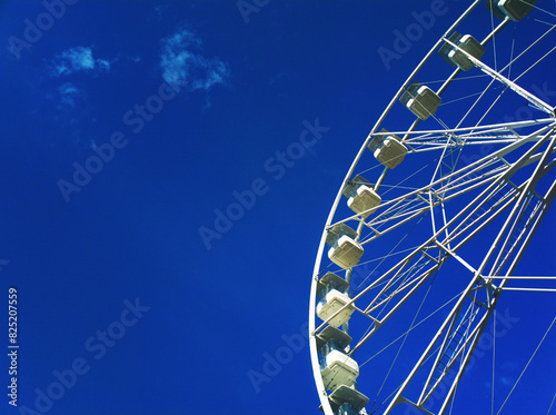 Right aligned white Ferris wheel on blue sky background
