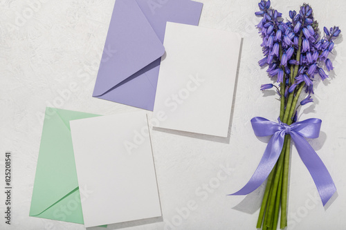 Bouquet of spring Scilla in lavender color, two envelopes and blank cards on a white background. Greeting card.