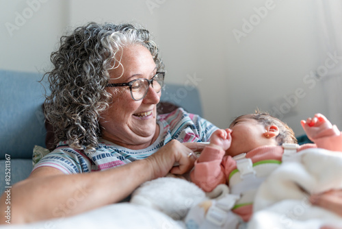 A smiling elderly woman cradling a newborn in a cozy room. photo